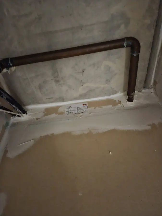 Copper pipes through a wall sealed with fire stopping and labelled